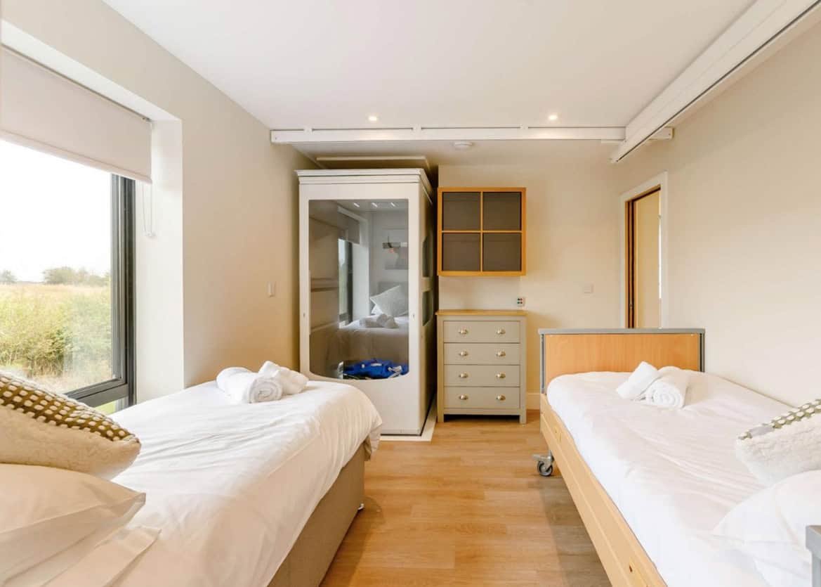 Bright modern twin bedroom with large window and mirror