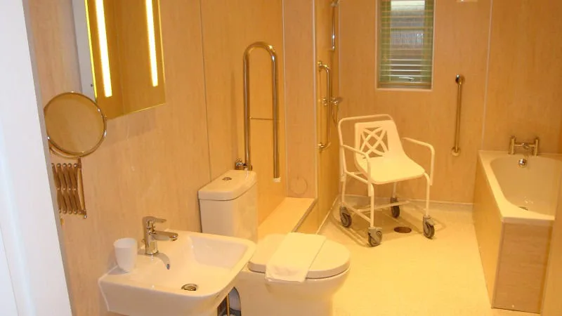 Accessible bathroom with grab bars and mobility chair