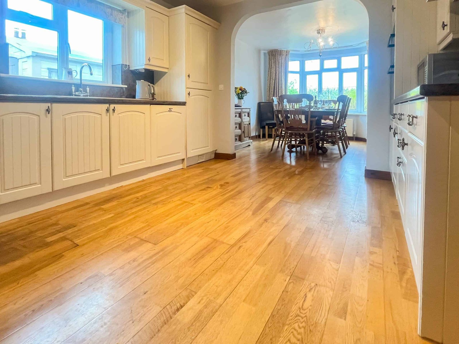 Bright kitchen leading to cozy dining room with hardwood floors