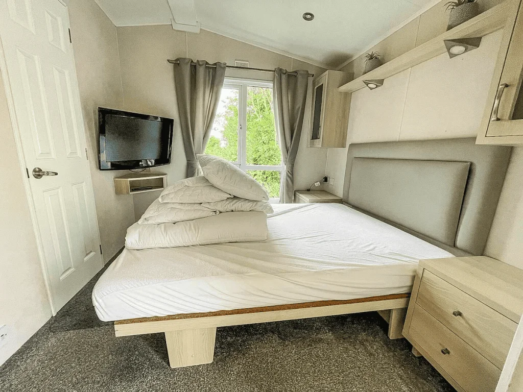 Modern bedroom with bed, TV, and window view