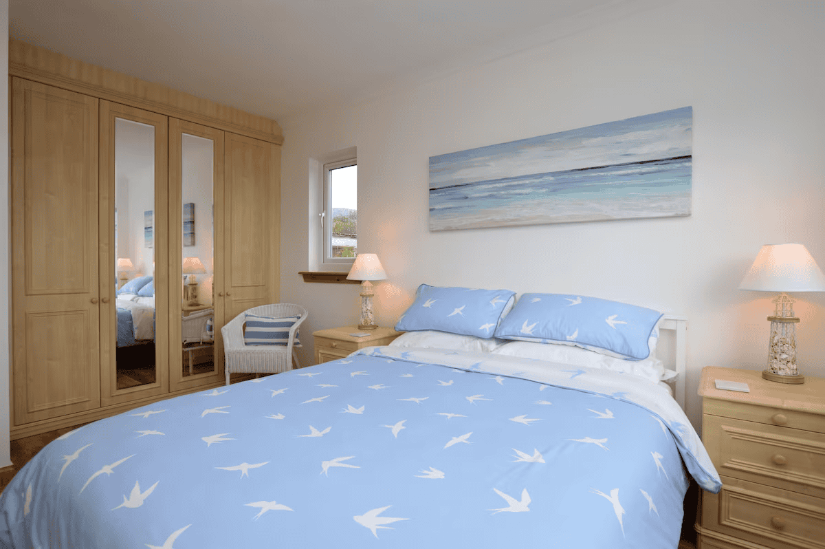 Cozy bedroom with seagull-patterned bedding and beach painting