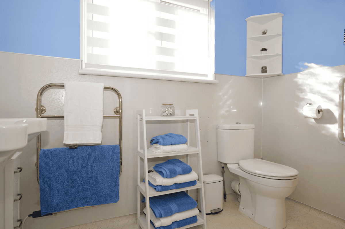 Bright bathroom with white fixtures and blue towels.