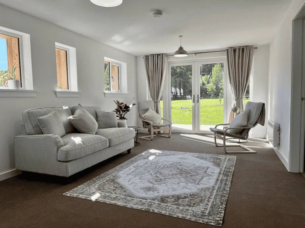 Bright living room with sofas, rug, and garden view.