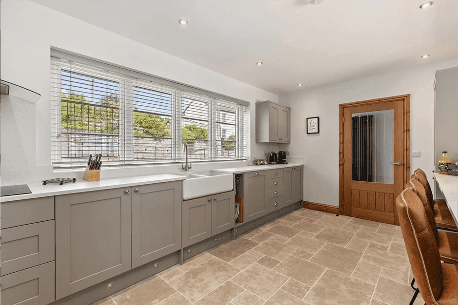 Bright modern kitchen with large windows and wooden door.