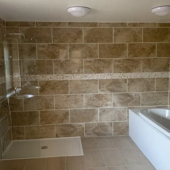 Modern beige tiled bathroom with glass shower