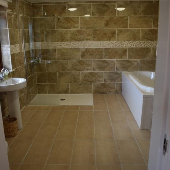 Modern beige tiled bathroom with shower and tub