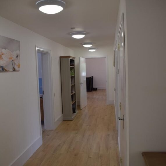 Bright office corridor with open doors and wall art