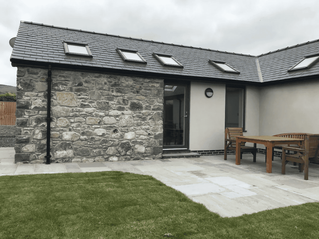 Stone house with slate roof and outdoor wooden furniture