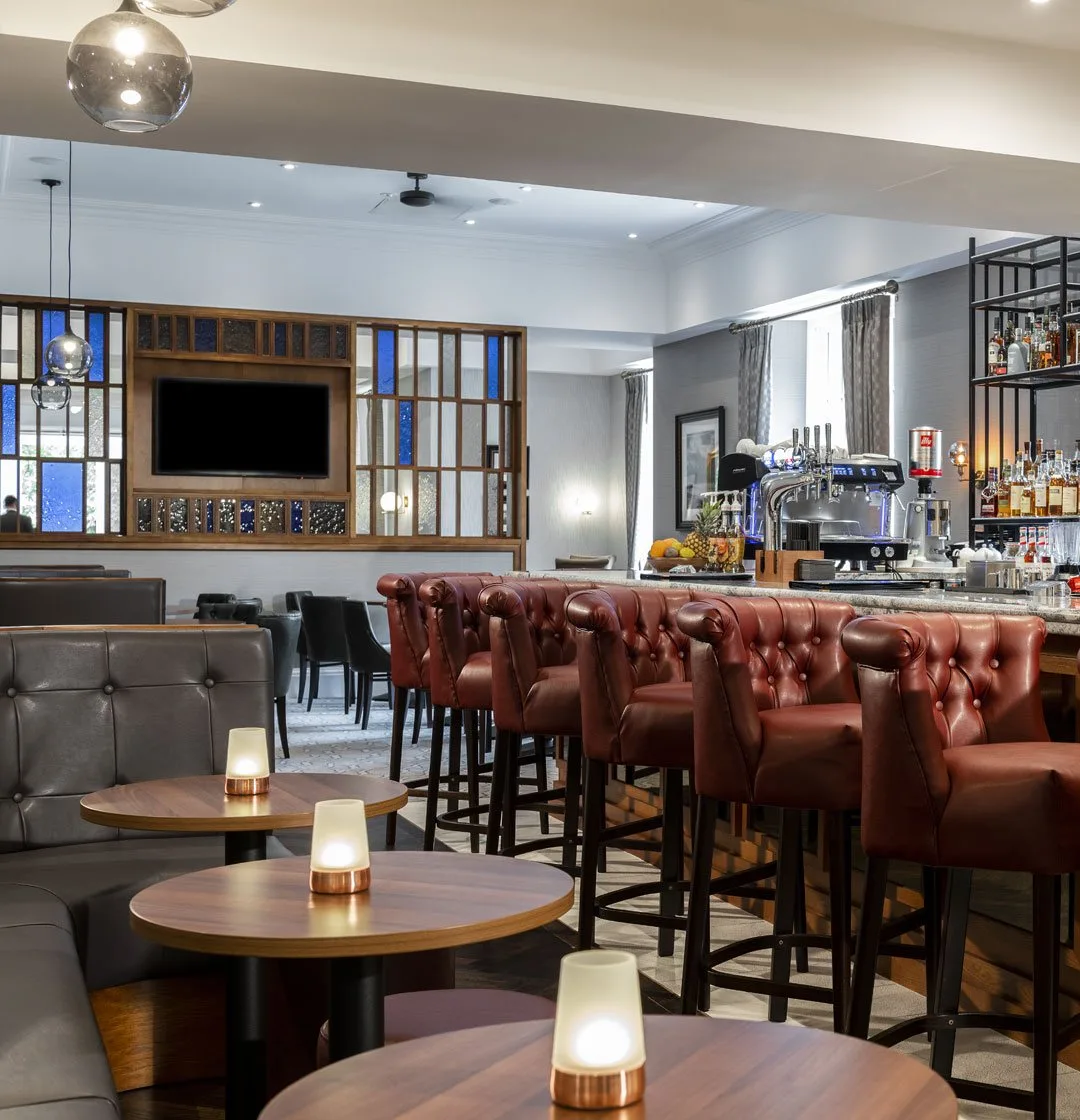 Elegant bar interior with leather stools and wooden tables