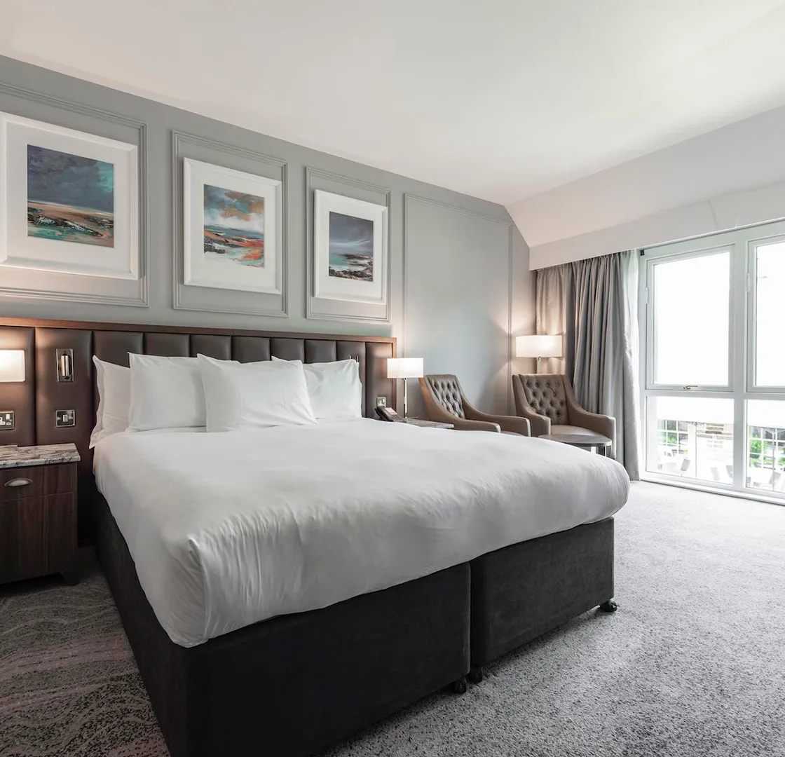 Elegant hotel room with large bed and scenic artworks