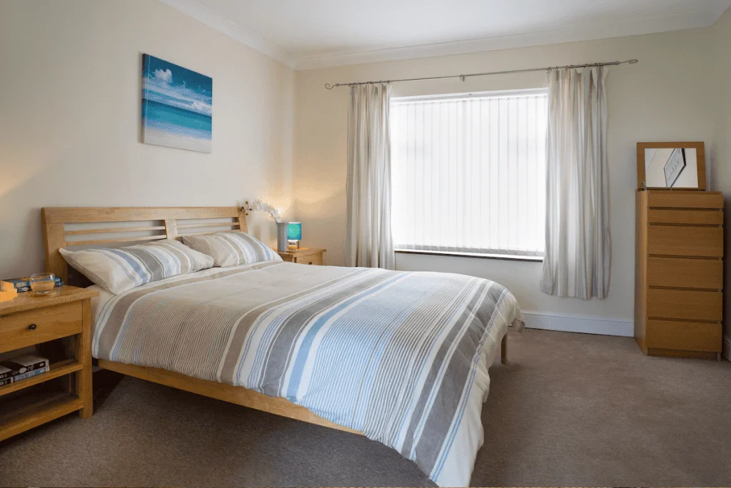 Spacious bedroom with wooden furniture and striped bedding