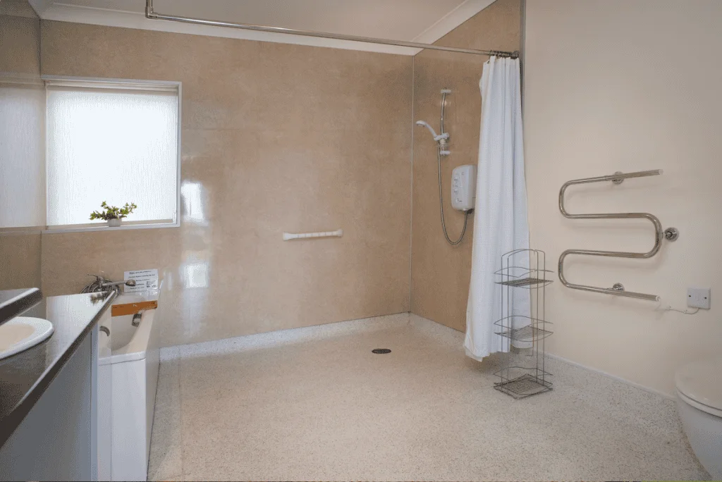Spacious accessible bathroom with shower, grab bars, and sink.