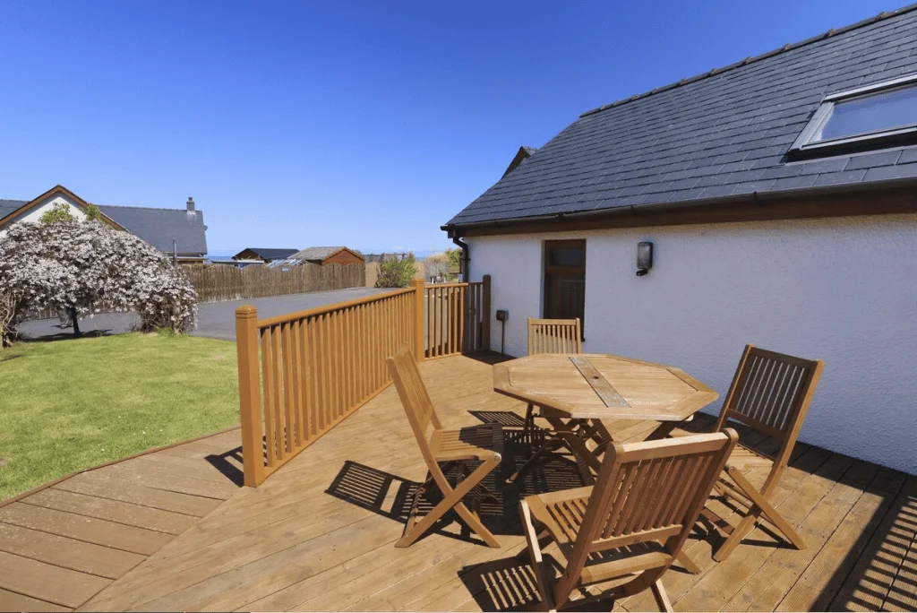 Sunny deck with wooden table, chairs, and ocean view