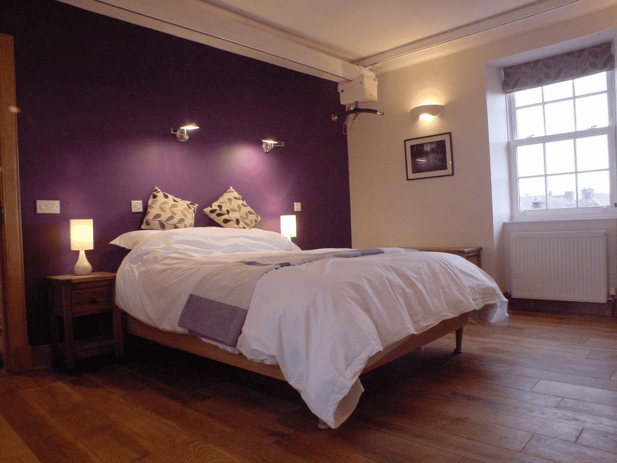 Cozy bedroom with purple walls and wooden flooring