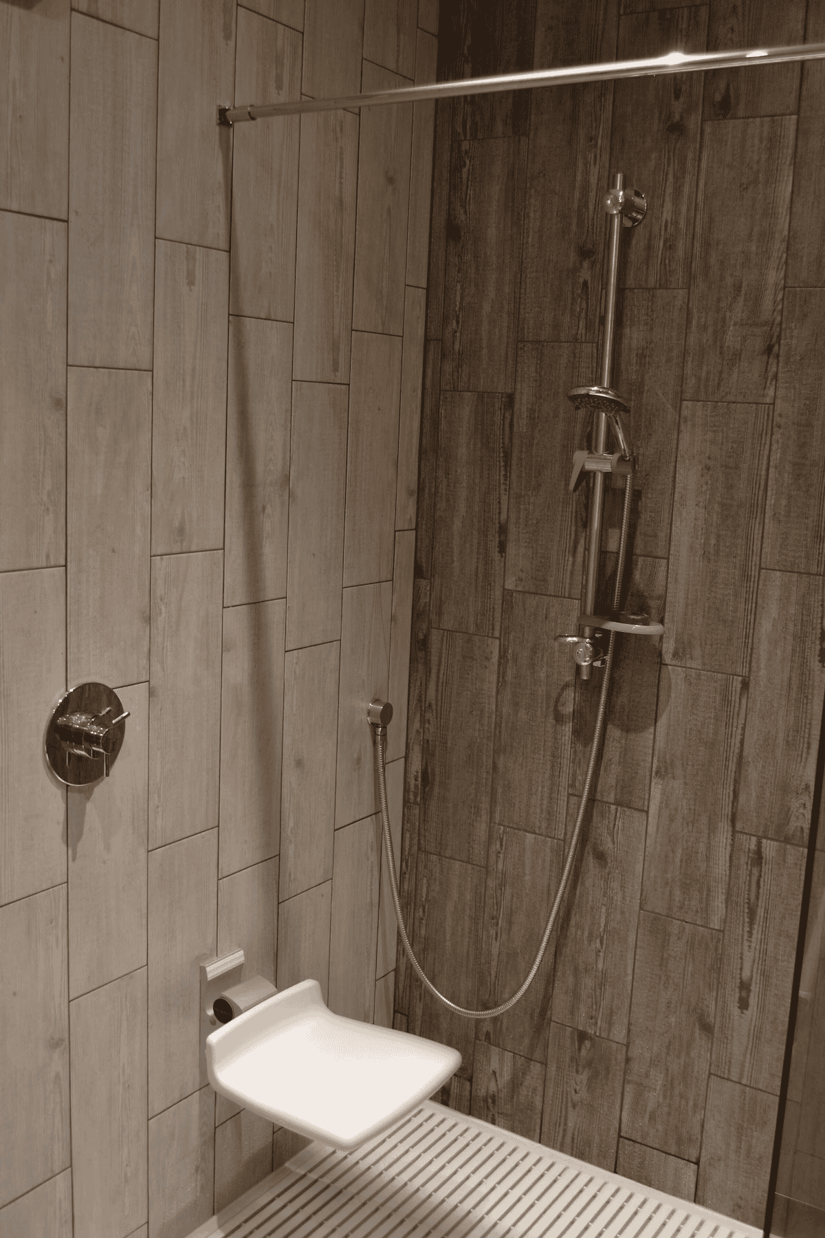 Modern shower with wooden tile walls and metal fixtures
