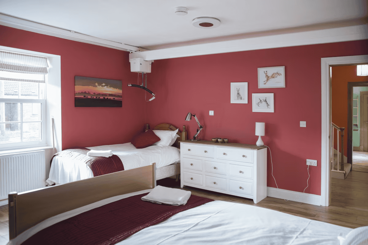 Spacious bedroom with red walls and white furniture