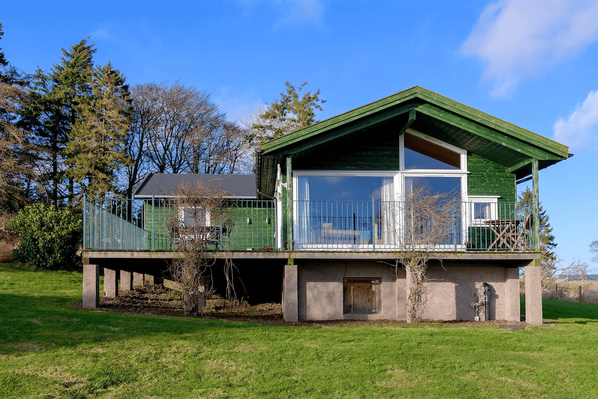 Green wooden house with balcony and panoramic windows
