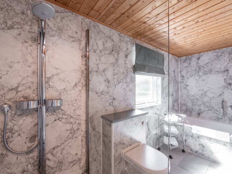 Modern bathroom with marble walls and wooden ceiling