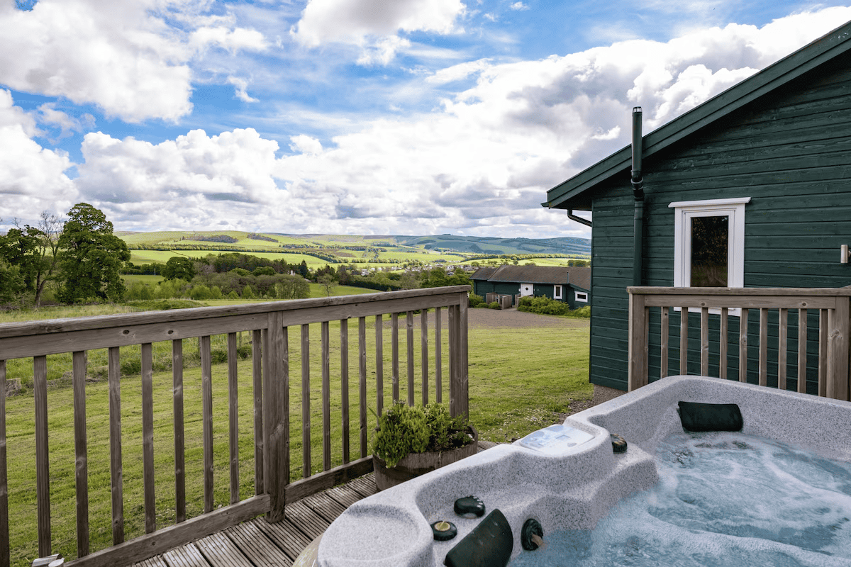 Hot tub on deck overlooking lush green hills