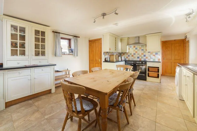 Spacious kitchen with wooden table and white cabinets