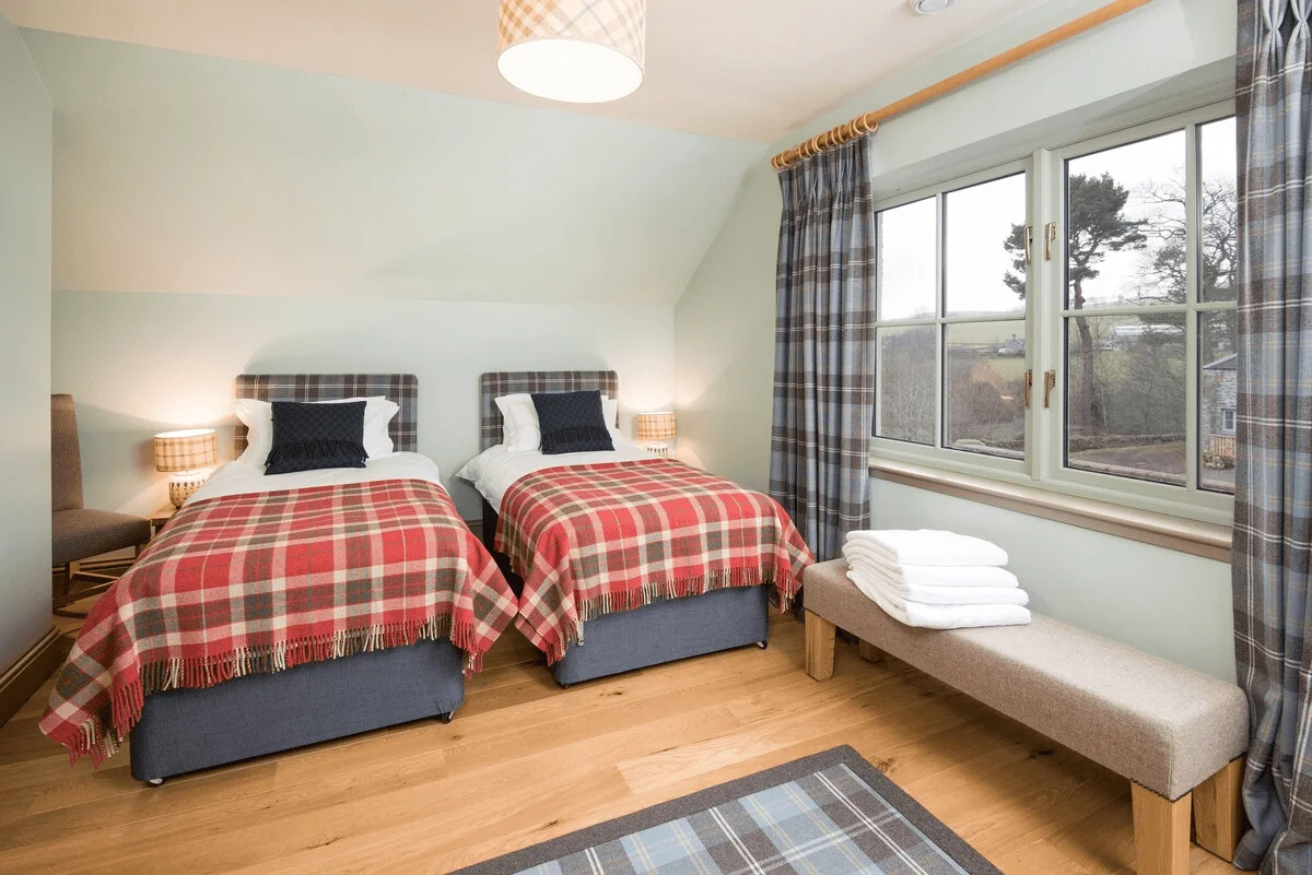 Cozy twin bedroom with plaid bedding and rural view