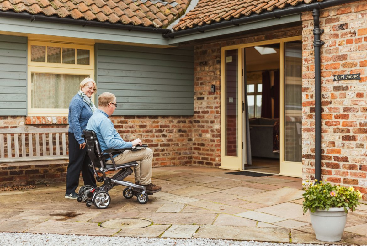 Man in wheelchair entering accessible home entrance.