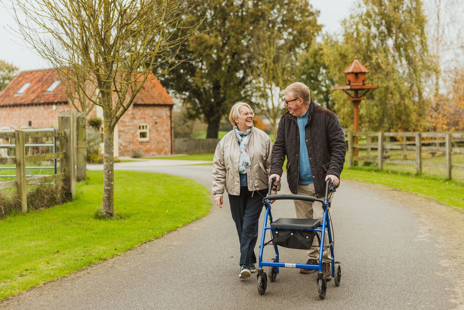 Elderly couple walking outdoors with a walker.