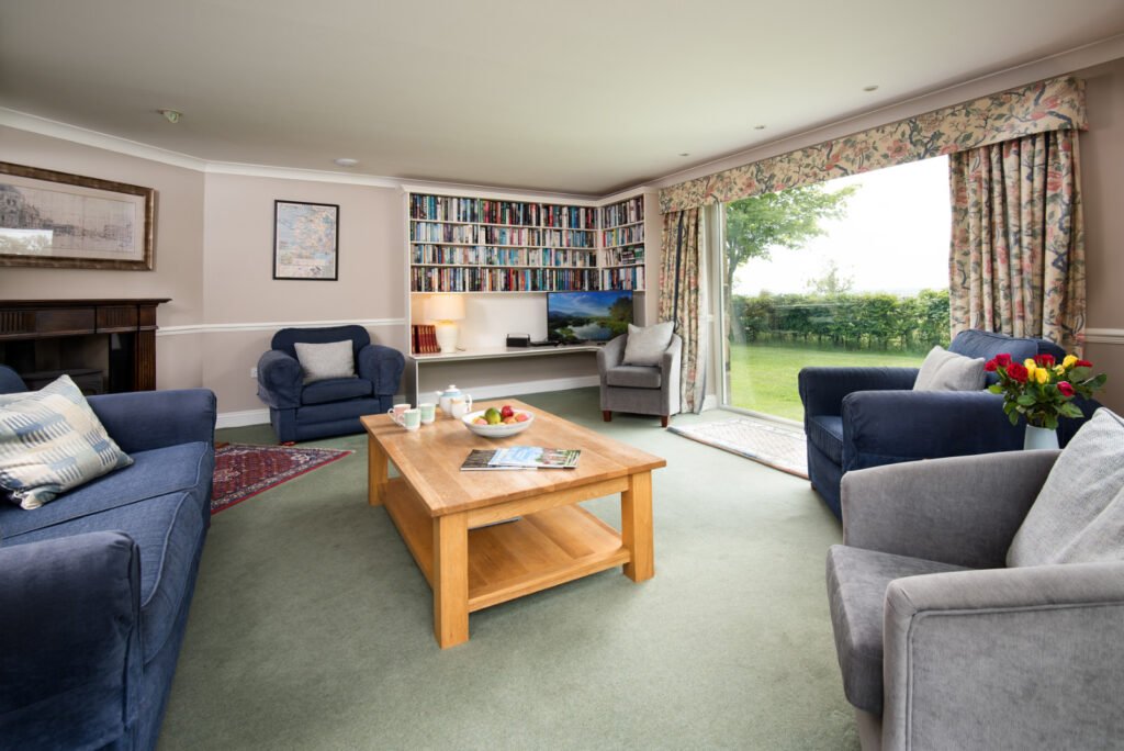 Cosy lounge with books, sofas, and garden view.