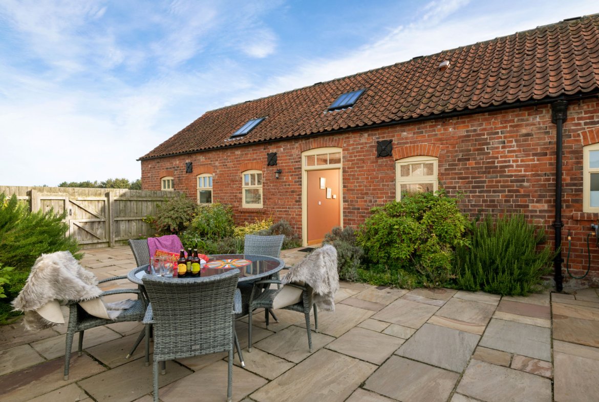 Charming brick cottage with outdoor patio furniture.