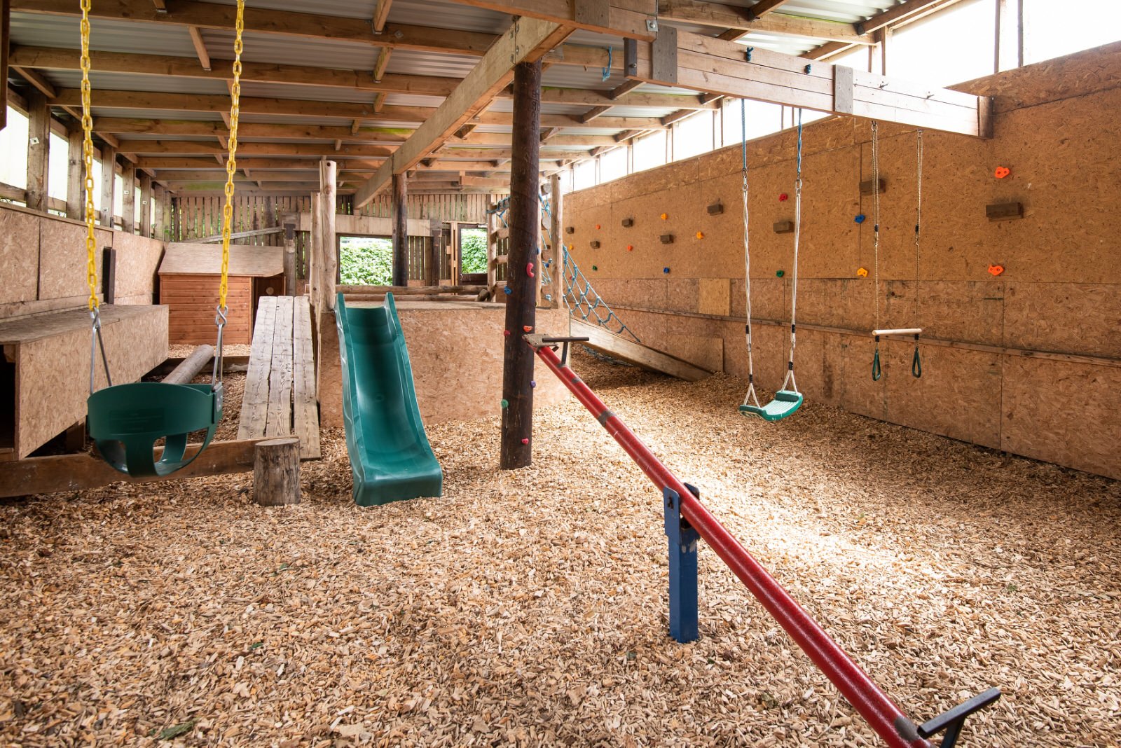Indoor playground with swings, slide, and seesaw