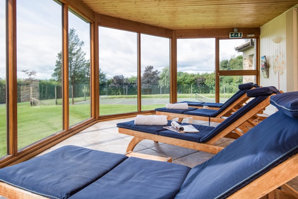 Relaxing indoor sunroom with loungers overlooking garden.
