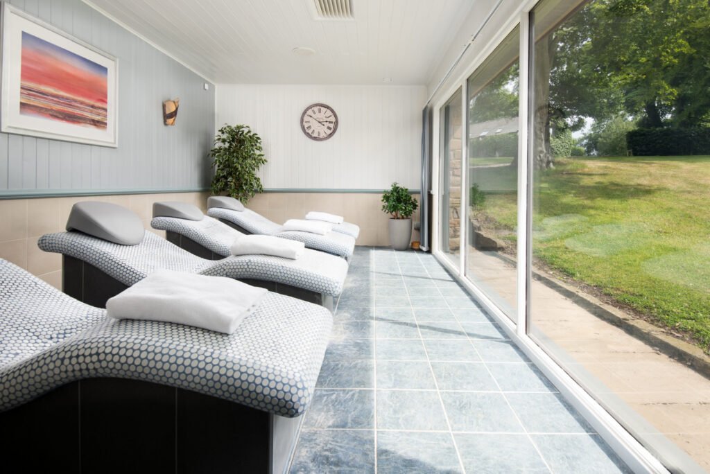Relaxing spa room with recliners and garden view.