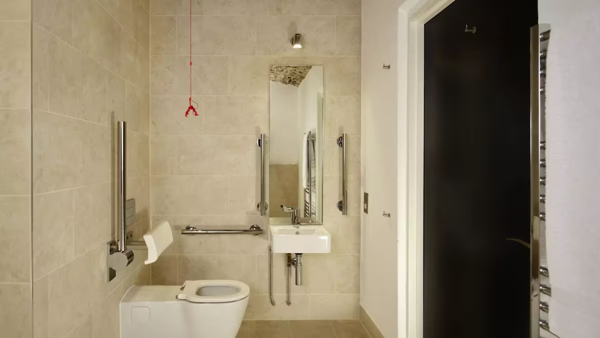 Accessible bathroom with support rails and emergency cord.