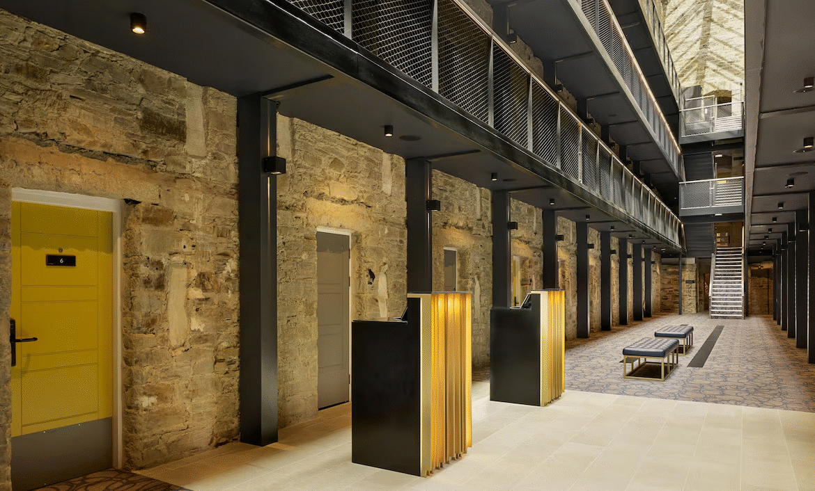 Modern hotel lobby with stone walls and metal stairs.