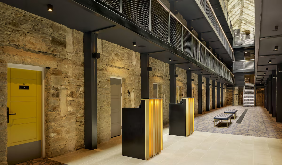 Modern hotel lobby with stone walls and metal stairs.