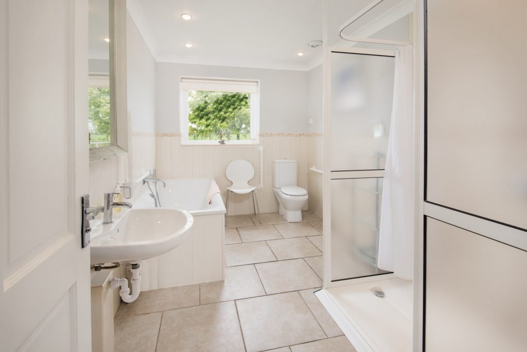 Modern bathroom with white fixtures and window view.