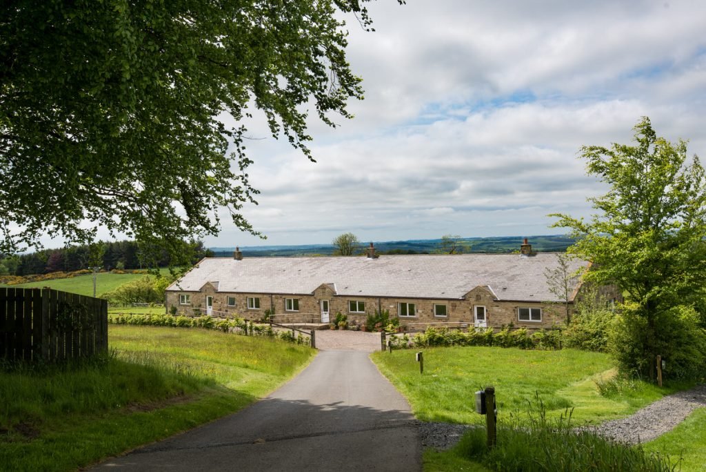 Stone cottage in lush countryside, under blue sky.