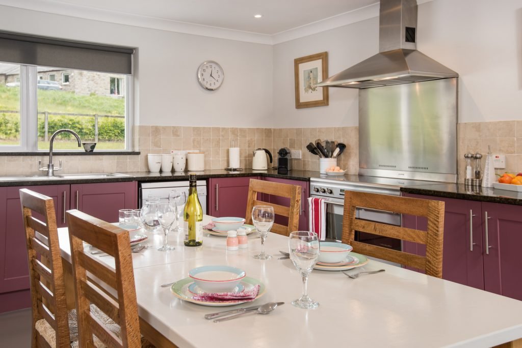 Modern kitchen with purple cabinets and dining table.