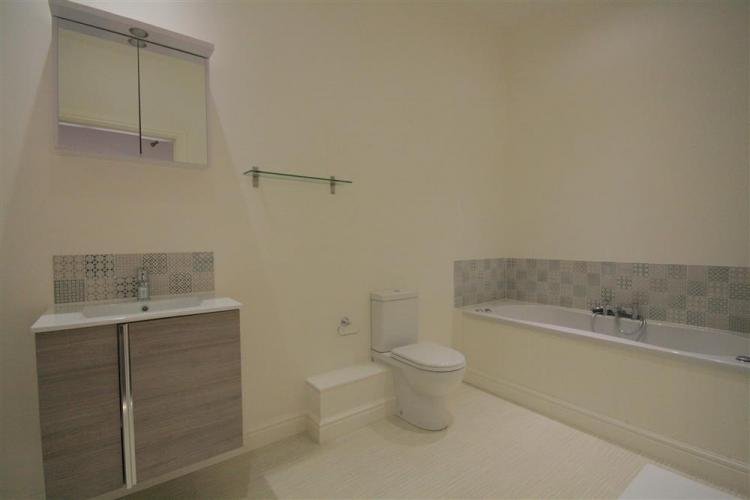 Modern bathroom with vanity, bathtub, and toilet.