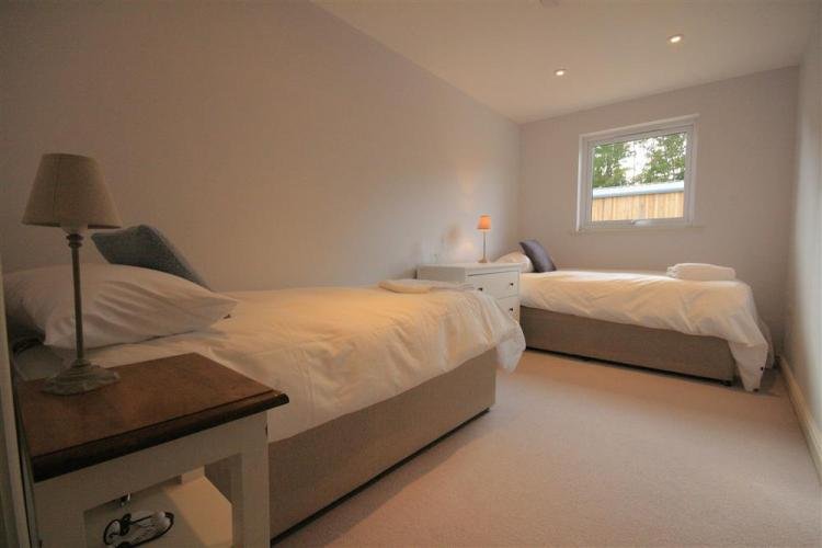 Twin beds in bright, cosy bedroom with lamps.
