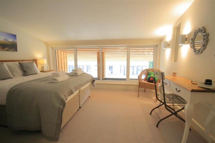 Spacious bedroom with large windows and desk area.