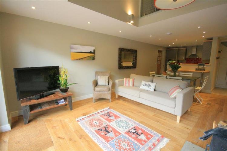 Modern living room with kitchen and seating area.